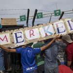 migrants-hold-a-banner-reading-merkel-in-front-of-a-barrier-at-the-border-with-hungary-near-the-village-of-horgos