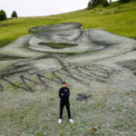 swiss-french-artist-saype-poses-next-to-his-land-art-painting-representing-a-child-drawing-at-the-col-de-bretaye-in-villars-sur-ollon