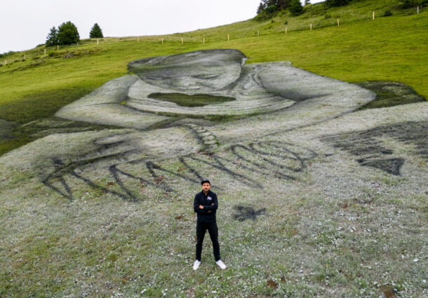 swiss-french-artist-saype-poses-next-to-his-land-art-painting-representing-a-child-drawing-at-the-col-de-bretaye-in-villars-sur-ollon