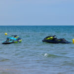two-personal-watercraft-waiting-for-riders-in-front-of-the-beach