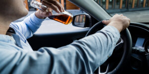 cropped-view-of-man-drinking-whiskey-while-driving-car-blurred-foreground