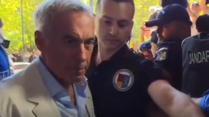 Momentul în care Georgescu a fost scos încătușat din casă. Doi polițiști îl țineau de brațe